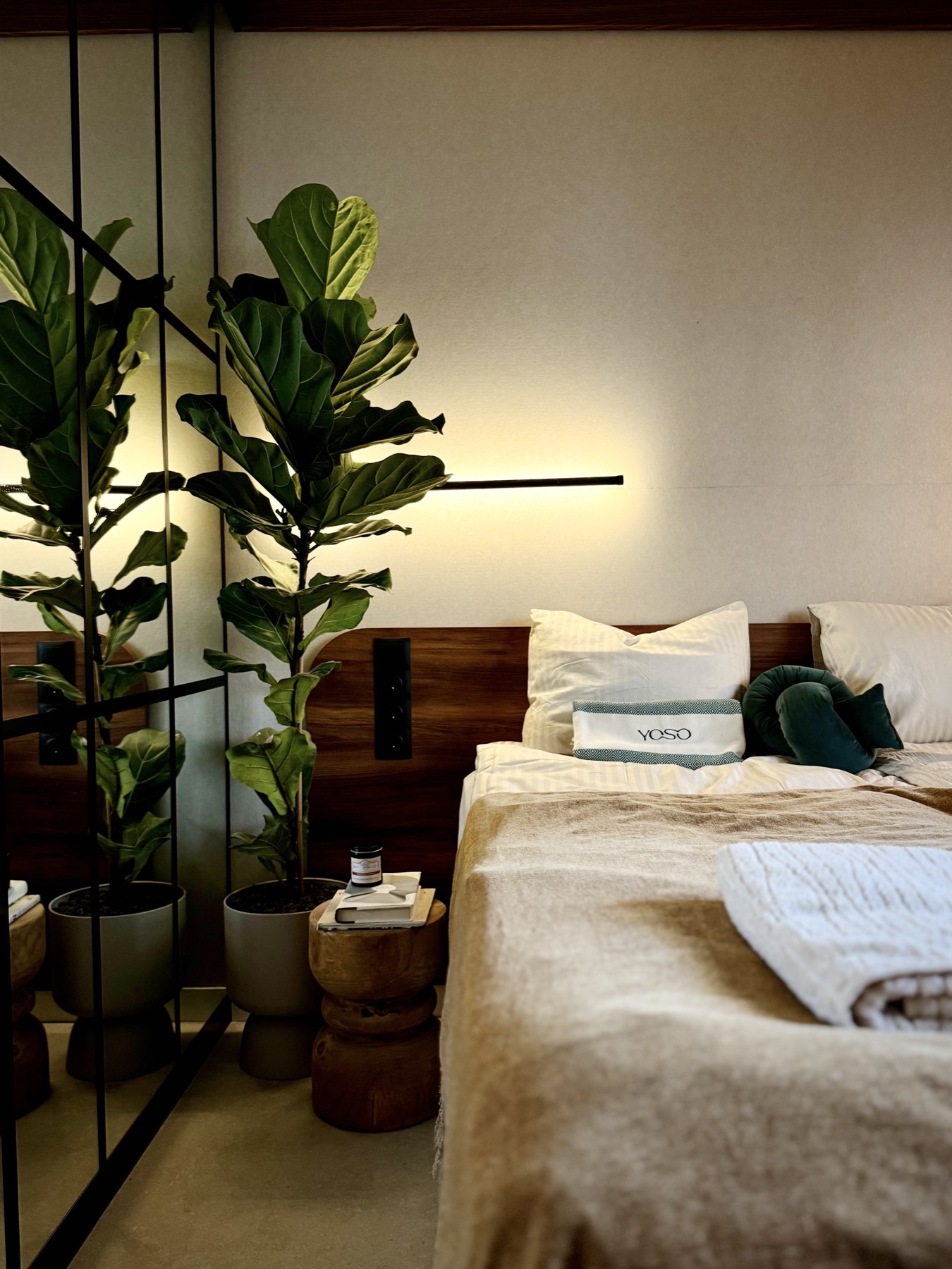 YOSO bedroom with a double bed, fiddle-leaf plants and warm light